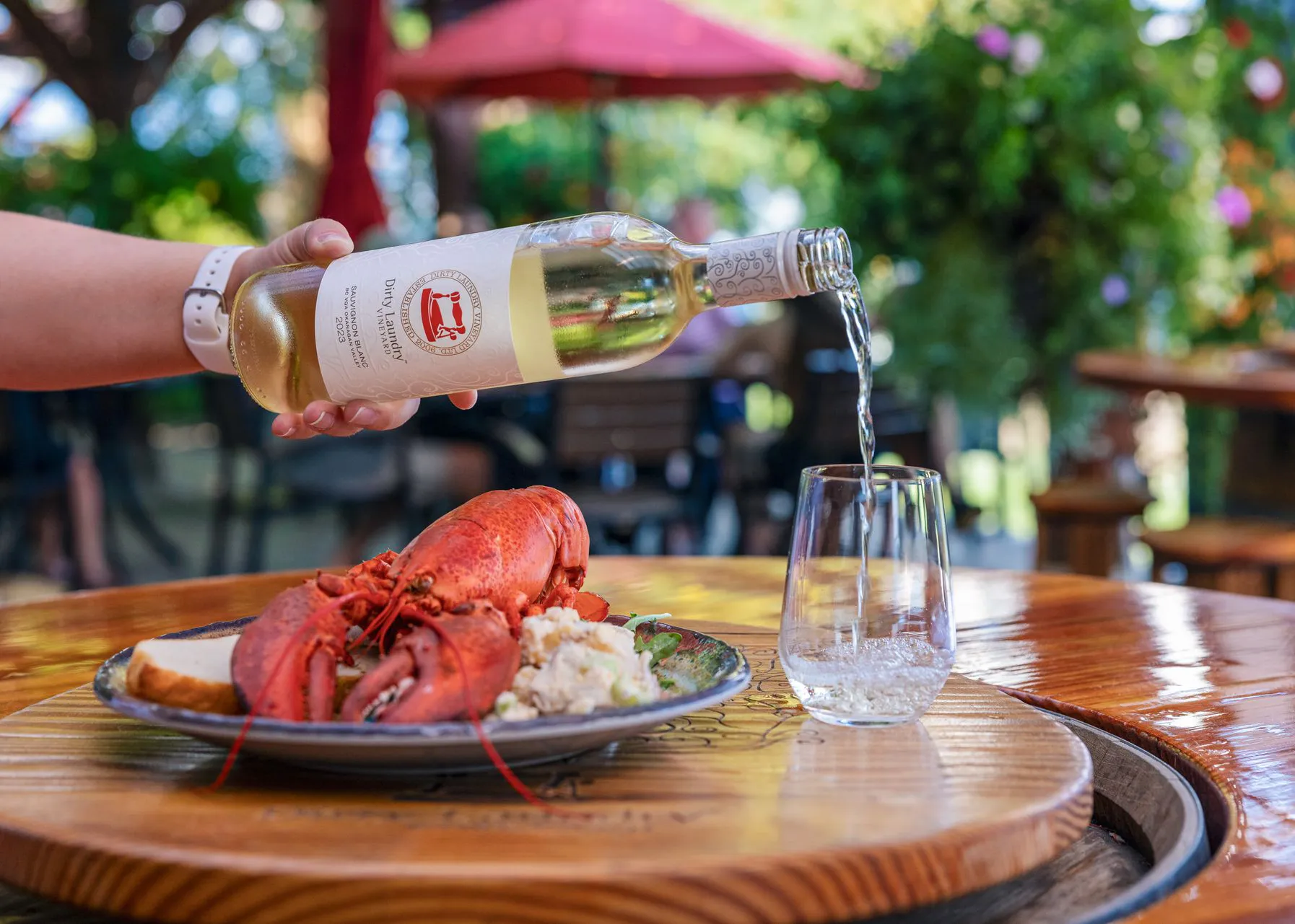 White wine pourerd into a glass with plate of lobster